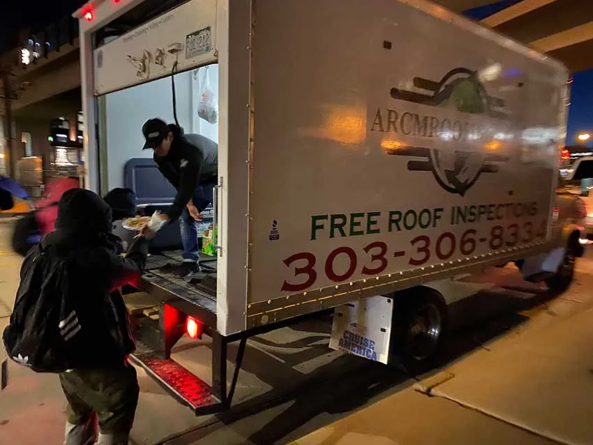 ARCM Roofing crew handing out hot Christmas plates from the ARCM box truck at night