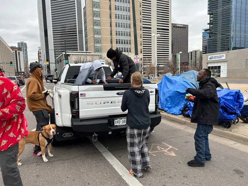 ARCM Roofing crew handing out food from a pickup truck to neighbors in downtown Denver
