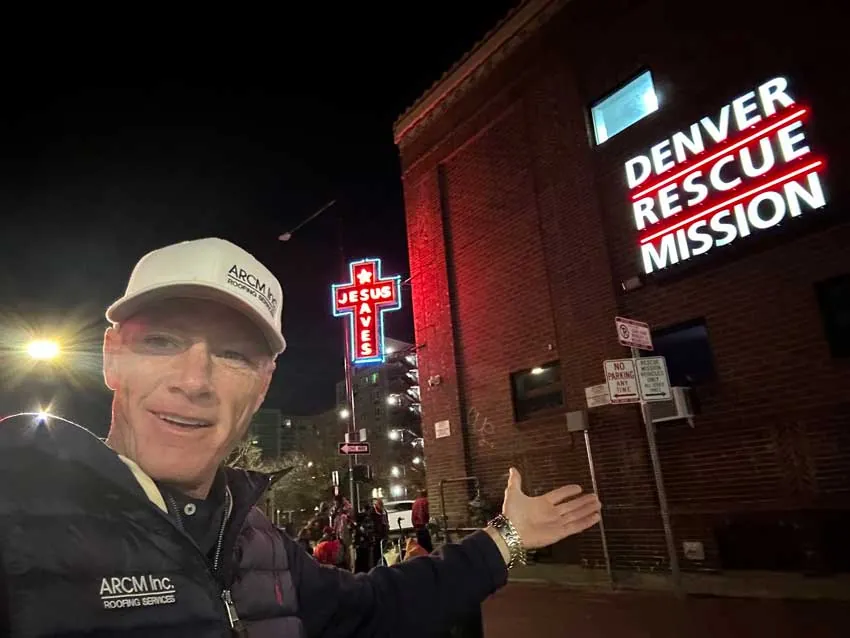 ARCM Roofing team member outside the Denver Rescue Mission on a winter night