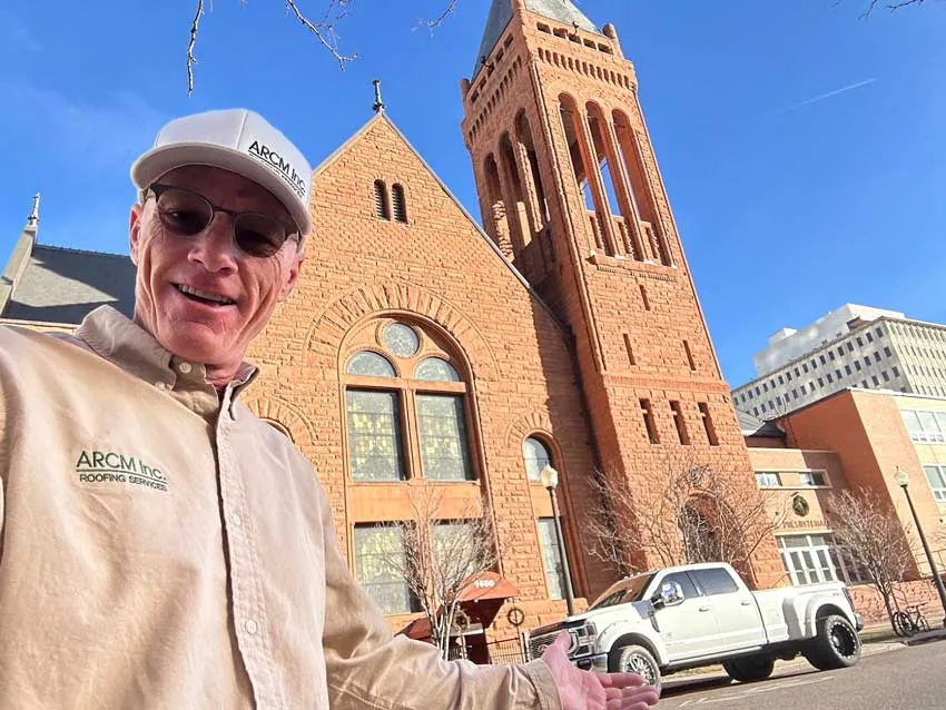 ARCM Roofing team member outside a historic downtown Denver church with the ARCM truck