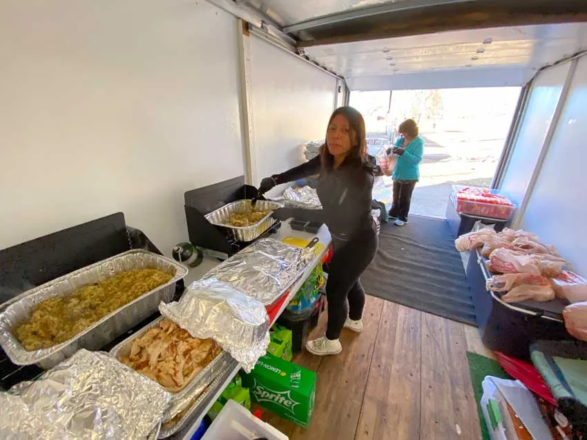 ARCM Cares volunteer serving stuffing and turkey inside the ARCM food trailer